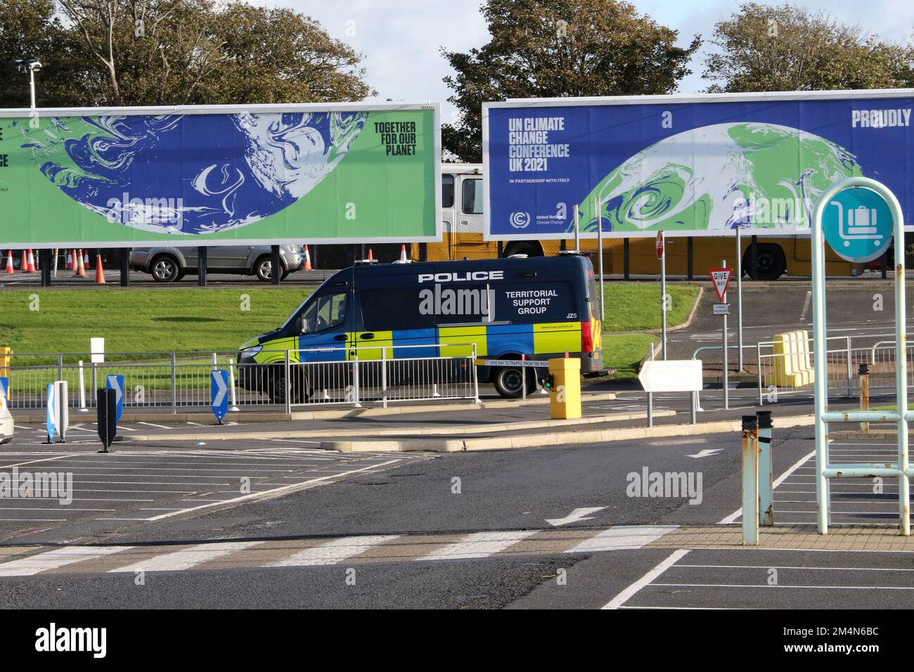 Glasgow Prestwick Airport, Prestwick, Ayrshire, Scotland, UK. Image shows large advertising hoarding promoting the UK Climate Change conference being held in Glasgow 2021. Known as COP 26. A Police van passes in front of he hoarding Stock Photo