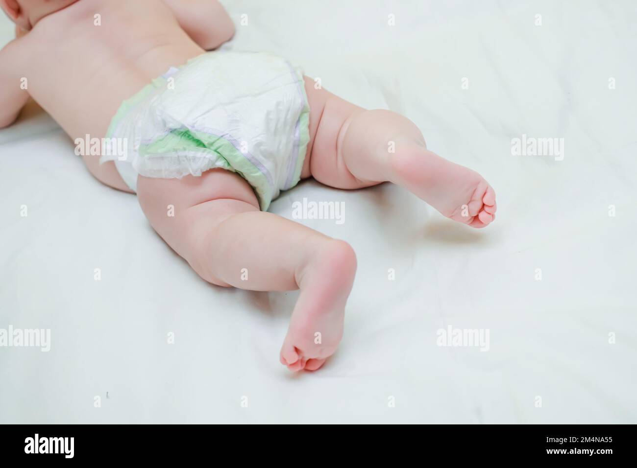 The legs of a newborn baby. Baby pink baby legs that learn to crawl in a crib with a white sheet