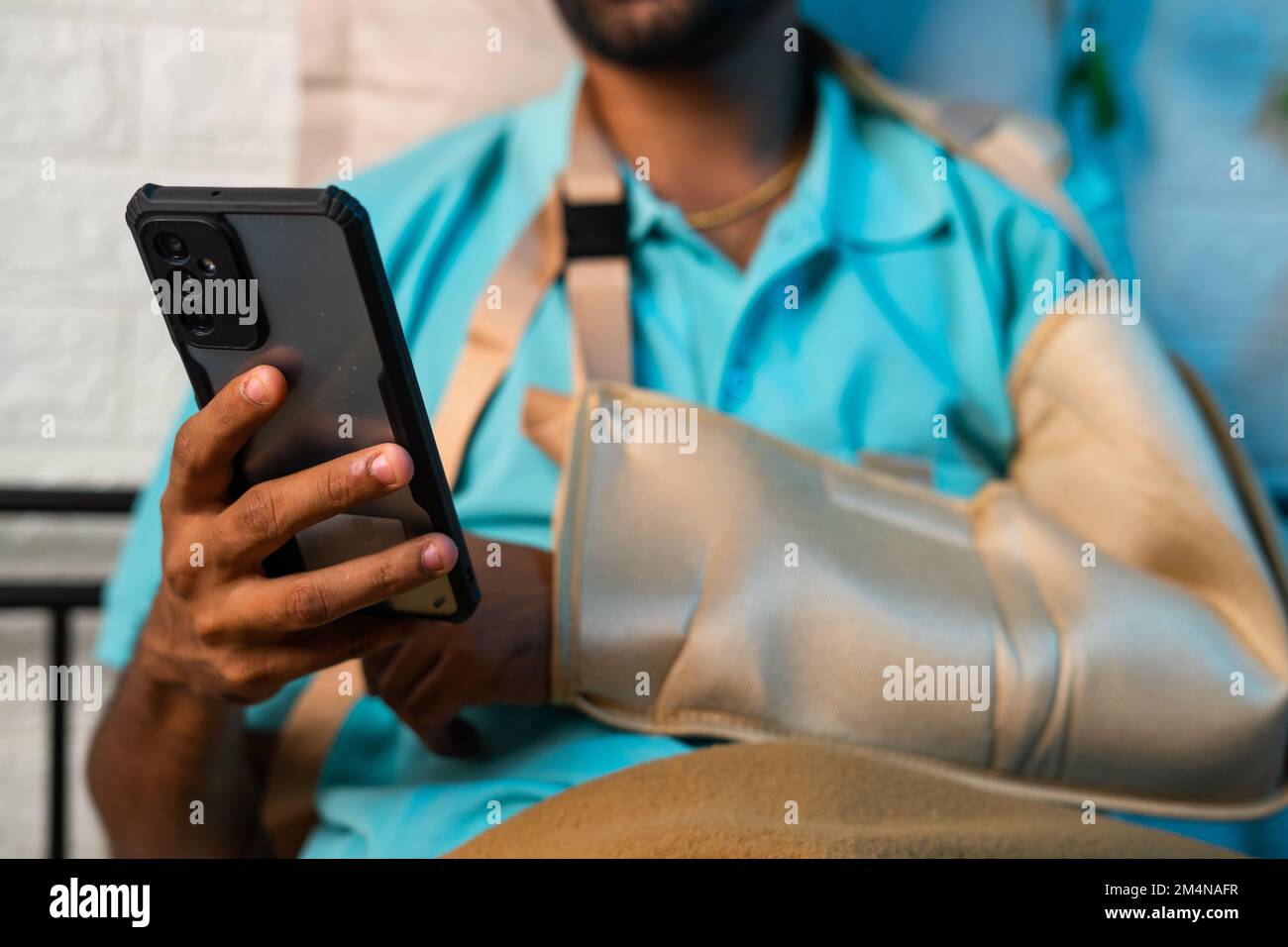 Close up shot of man using mobile phone from broken hand at home - concept of social media addiction, relaxation and treatment. Stock Photo