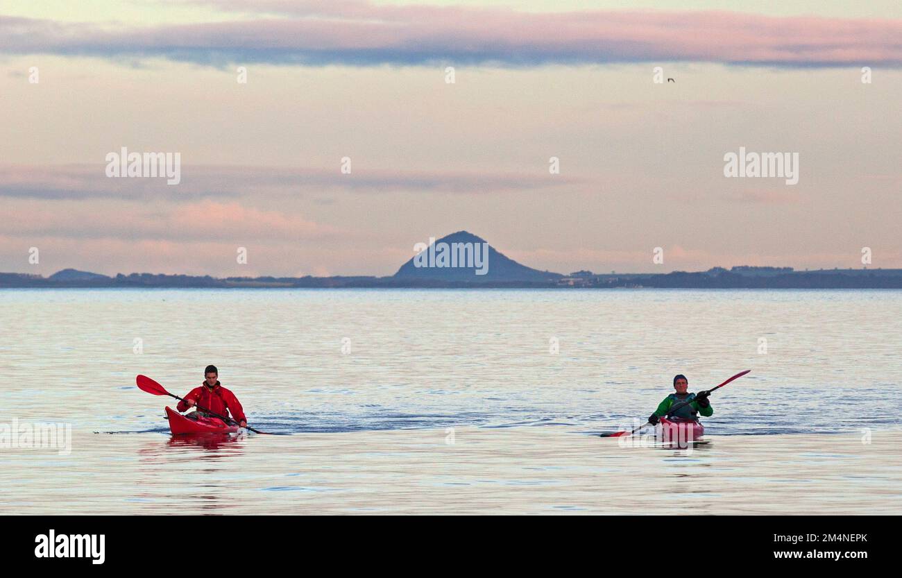 Portobello, Edinburgh, Scotland, UK. 22nd December 2022.  Calm cloudy weather making  a smooth surface on the Firth of Forth for those involved in watersports. Temperature a cool 6 degrees centigrade. Pictured: Two males in kayaks paddling towards the shore with Berwick Law in background. Credit: ArchWhite/alamy live news. Stock Photo