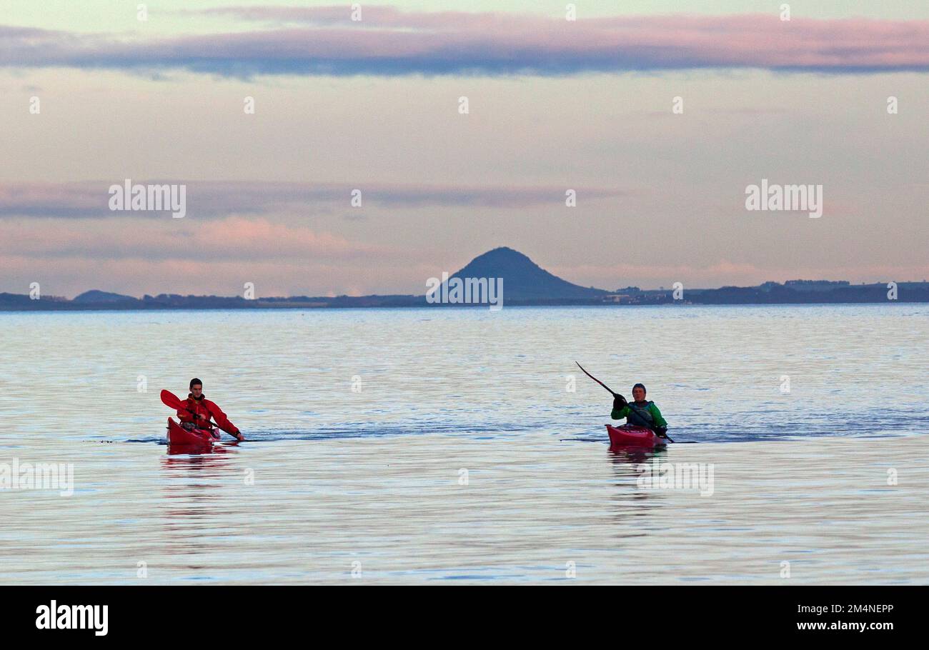 Portobello, Edinburgh, Scotland, UK. 22nd December 2022.  Calm cloudy weather making  a smooth surface on the Firth of Forth for those involved in watersports. Temperature a cool 6 degrees centigrade. Pictured: Two males in kayaks paddling towards the shore with Berwick Law in background. Credit: ArchWhite/alamy live news. Stock Photo