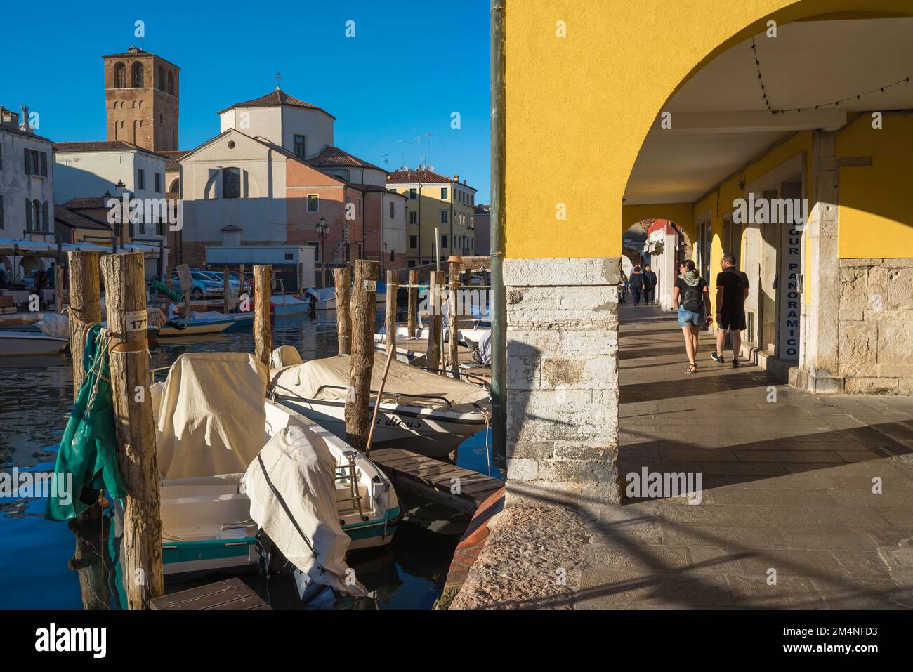 Veneto tourism, view in summer of a young couple wandering under historic colonnades in the scenic Venetian town of Chioggia, Veneto, Italy Stock Photo
