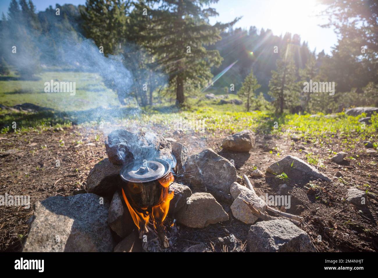 Touristic kettle on fire of burning campfire in camping in the hike. Cooking food in forest on