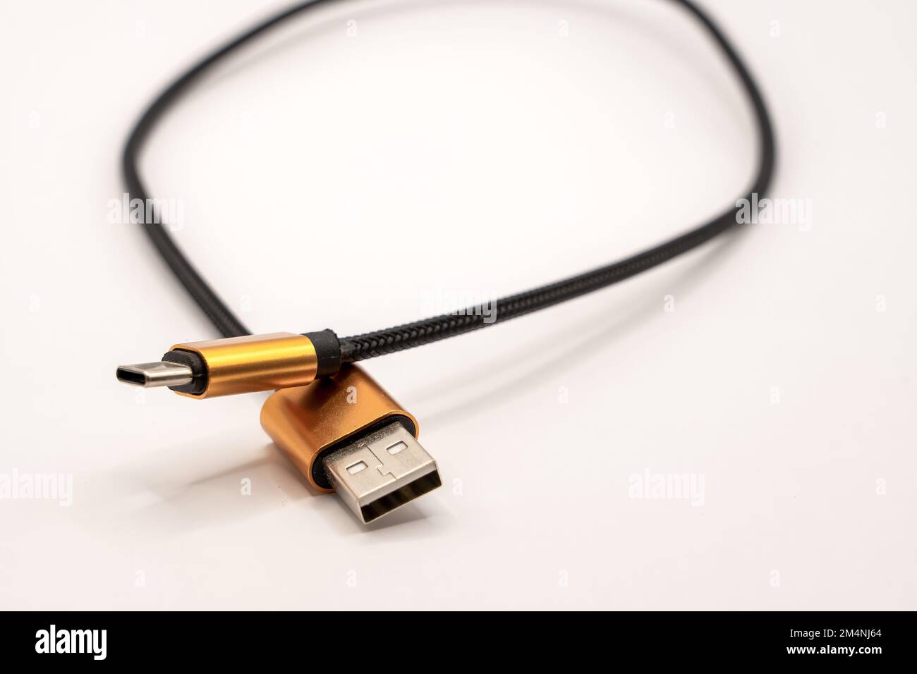 detailed close up of a black braided USB 2 to USB-C male cable with golden colour connectors Stock Photo