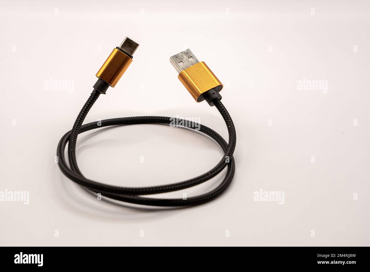 detailed close up of a black braided USB 2 to USB-C male cable with golden colour connectors Stock Photo