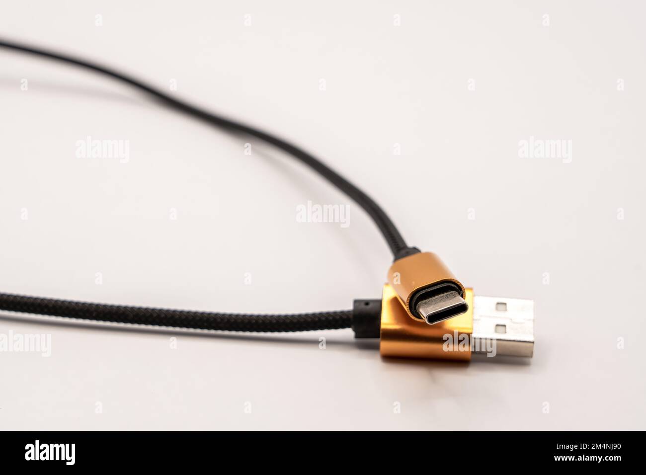 detailed close up of a black braided USB 2 to USB-C male cable with golden colour connectors Stock Photo