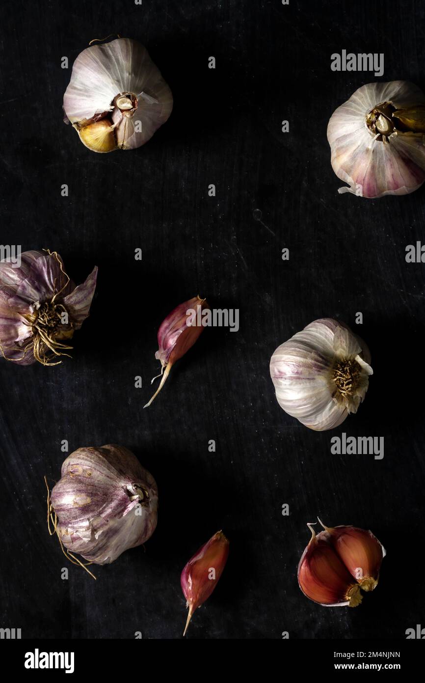Fresh garlic bulbs and cloves grouped on black background. Flat lay ...