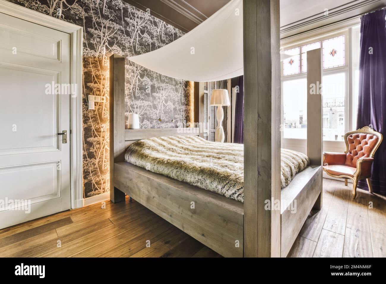 a bed in a room with wood flooring and wallpaper on the walls behind it