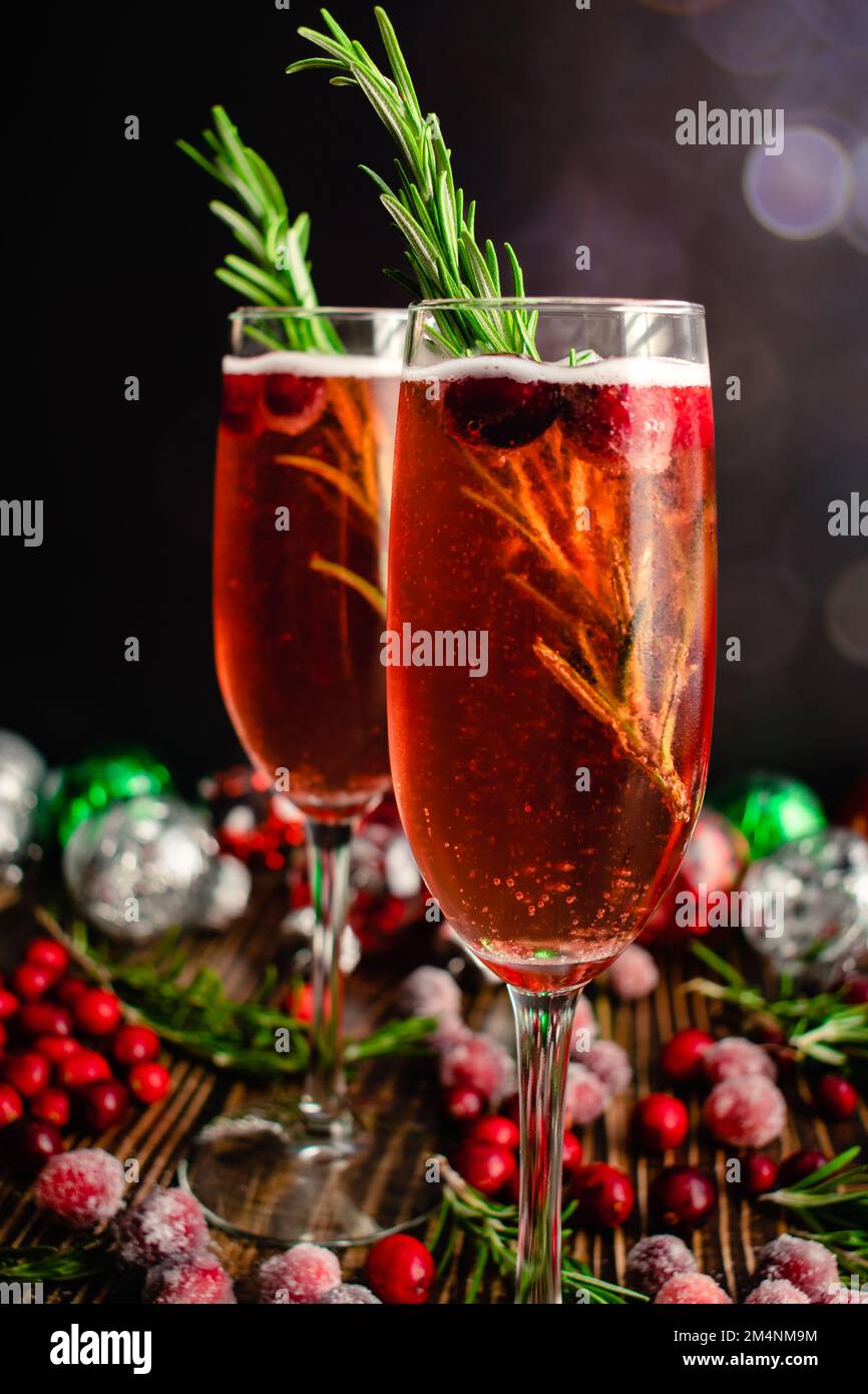 Christmas Mimosas Garnished with Sugared Cranberries and Rosemary: Champagne cocktails made with cranberry juice served in flute glasses Stock Photo
