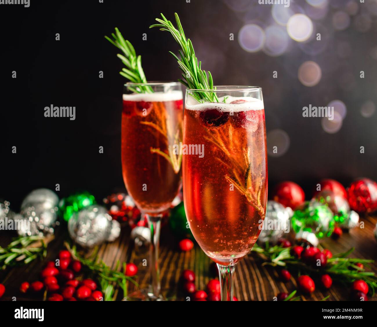 Christmas Mimosas Garnished with Sugared Cranberries and Rosemary: Champagne cocktails made with cranberry juice served in flute glasses Stock Photo