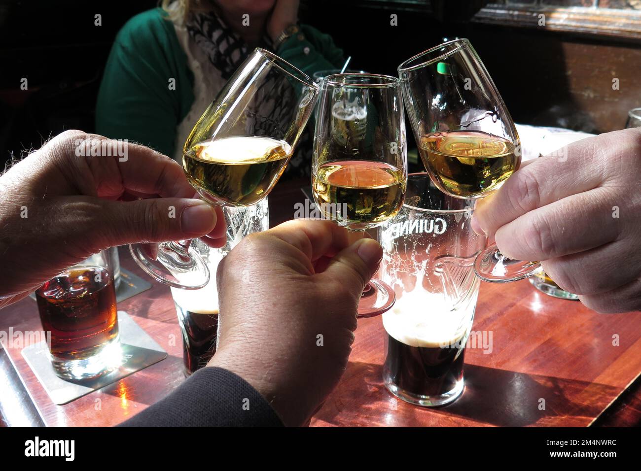 Three whisky glasses being raised and toasted in a Glasgow pub in the