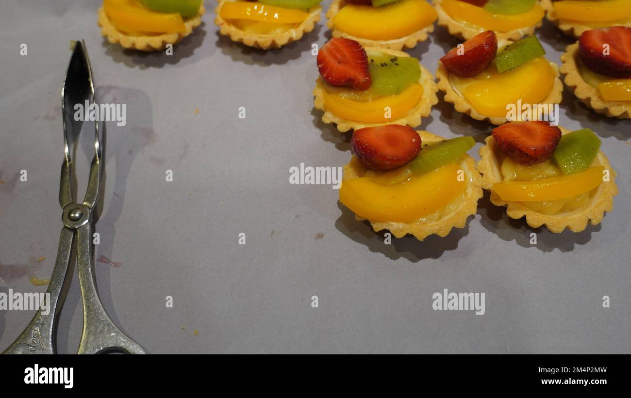 Dessert slice of strawberry , kiwi and orange fruit above small cake Stock Photo