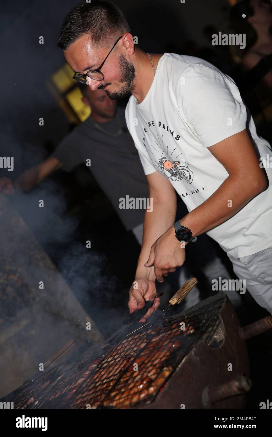 A young man cooking sausages on a bbq. Stock Photo