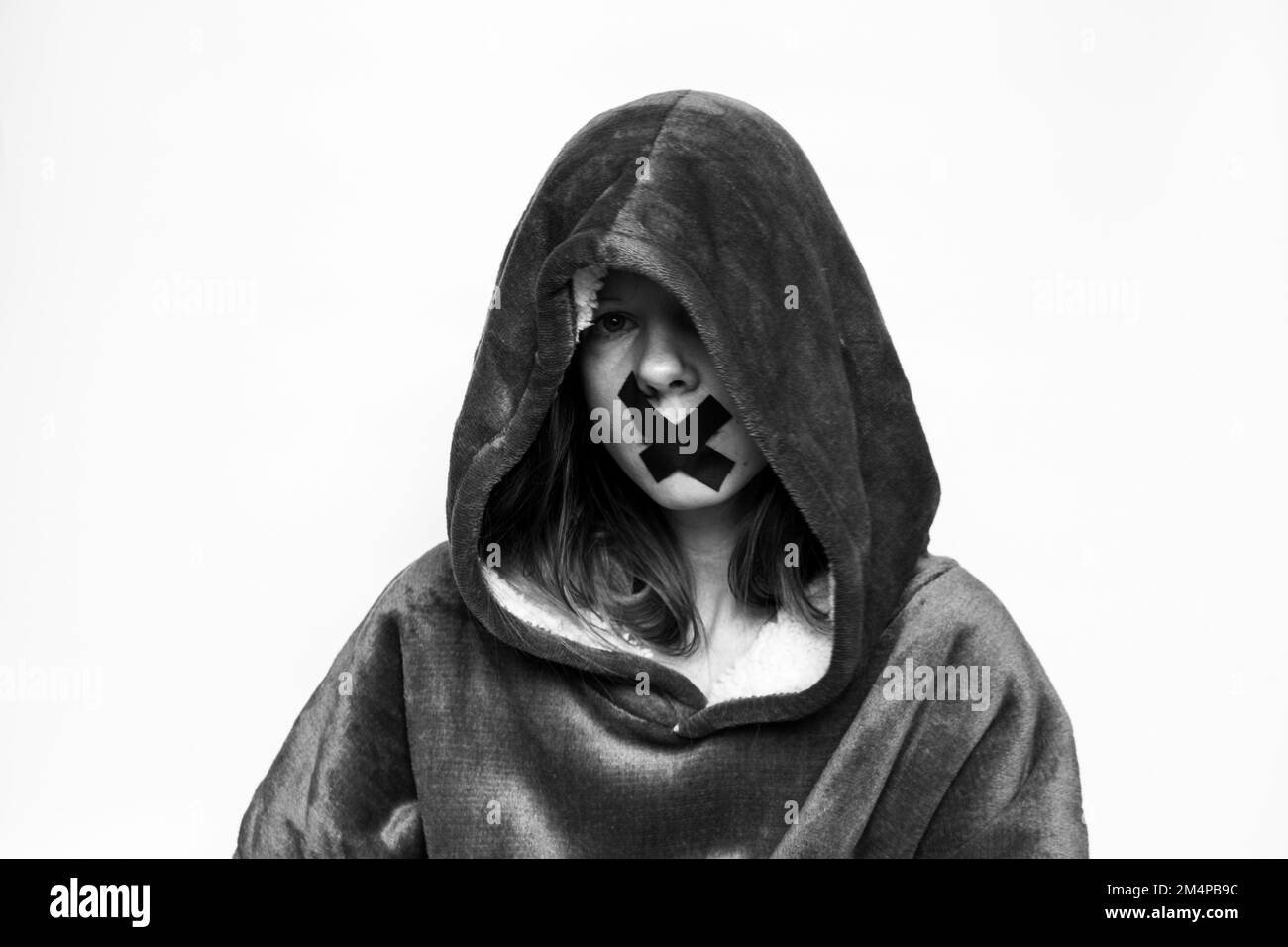 Girl with a sealed mouth in a sweatshirt with a hood on an isolated background, be silent and do not say anything, a secret Stock Photo