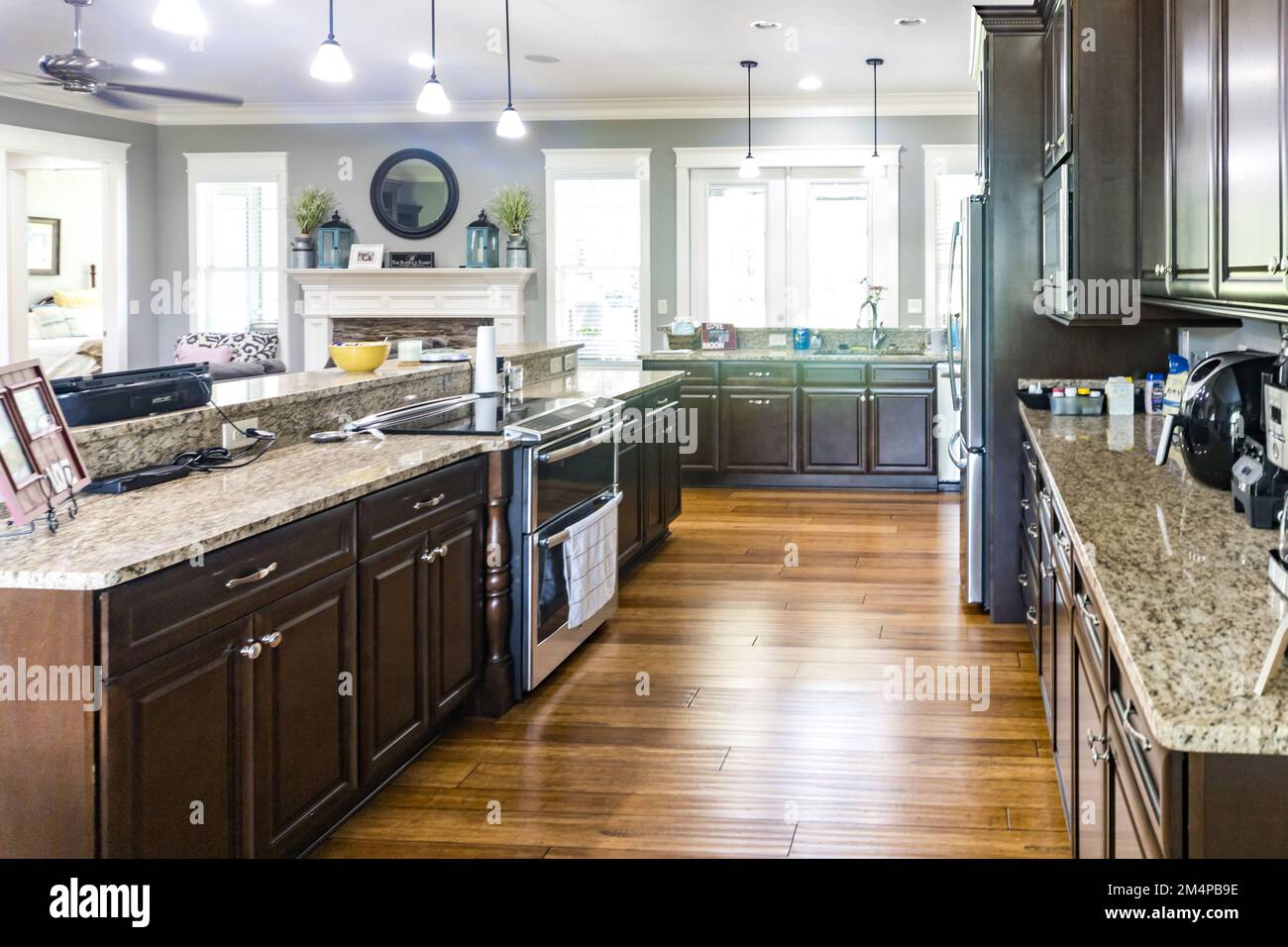 A new kitchen with dark wood cabinets, hardwood floors and stainless steel appliances Stock Photo
