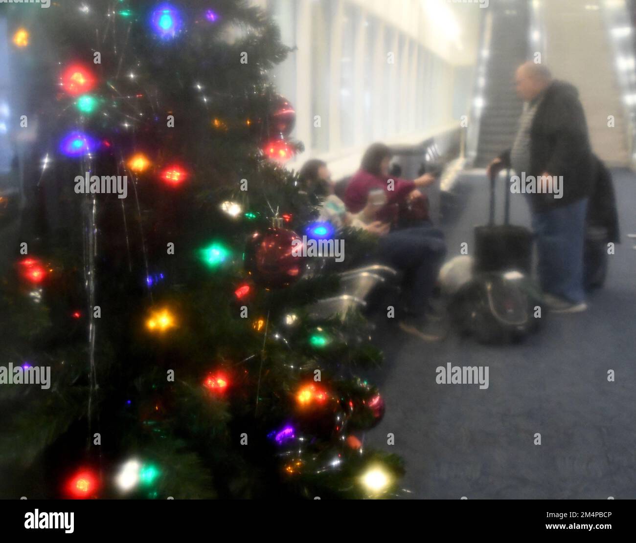 Milwaukee, Wisconsin, USA. 22nd Dec, 2022. A Christmas tree and passengers  are seen through a glass block window at Milwaukee Mitchell International  Airport in Milwaukee, Wisconsin, Thursday December 22, 2022. (Credit Image:  ©