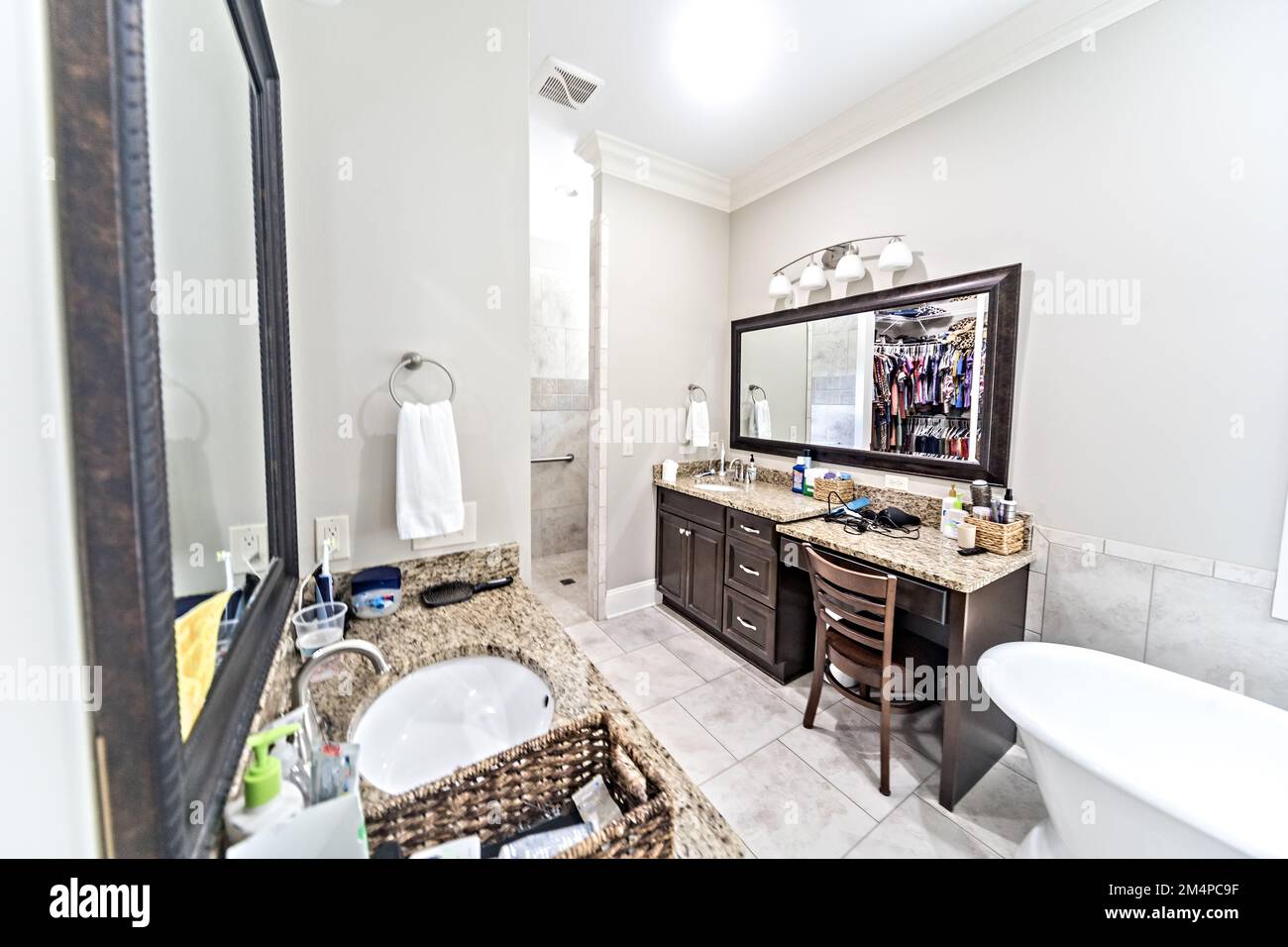A large master bathroom with tile floors, dark wood vanity and