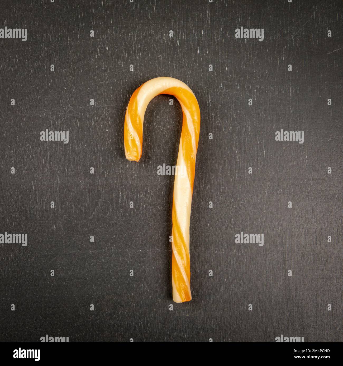 Orange cane candy, lollipop on a dark chalkboard background. Stock Photo