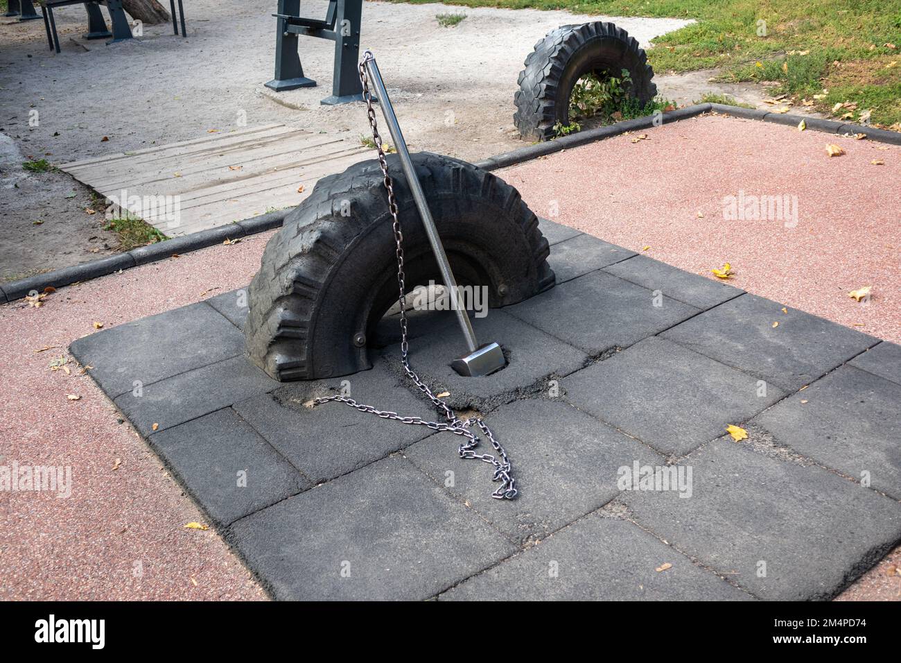 Sports ground equipment, tire with sledgehammer on chain on rubber mat