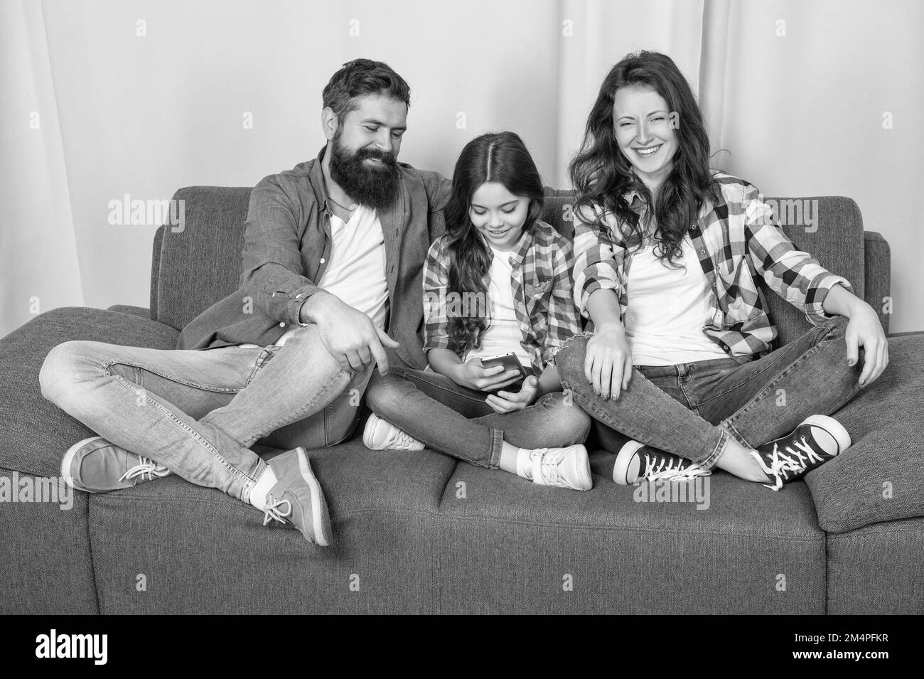 Smartphone obsessed kid. Child use mobile phone sitting next to parents