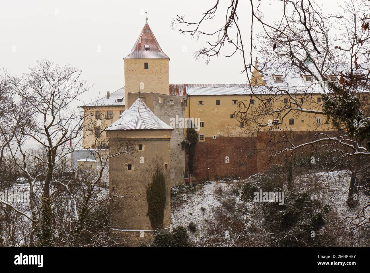 Deer Moat and Daliborka tower in foreground with snow-covered roofs of Prague Castle in winter, no people. Stock Photo