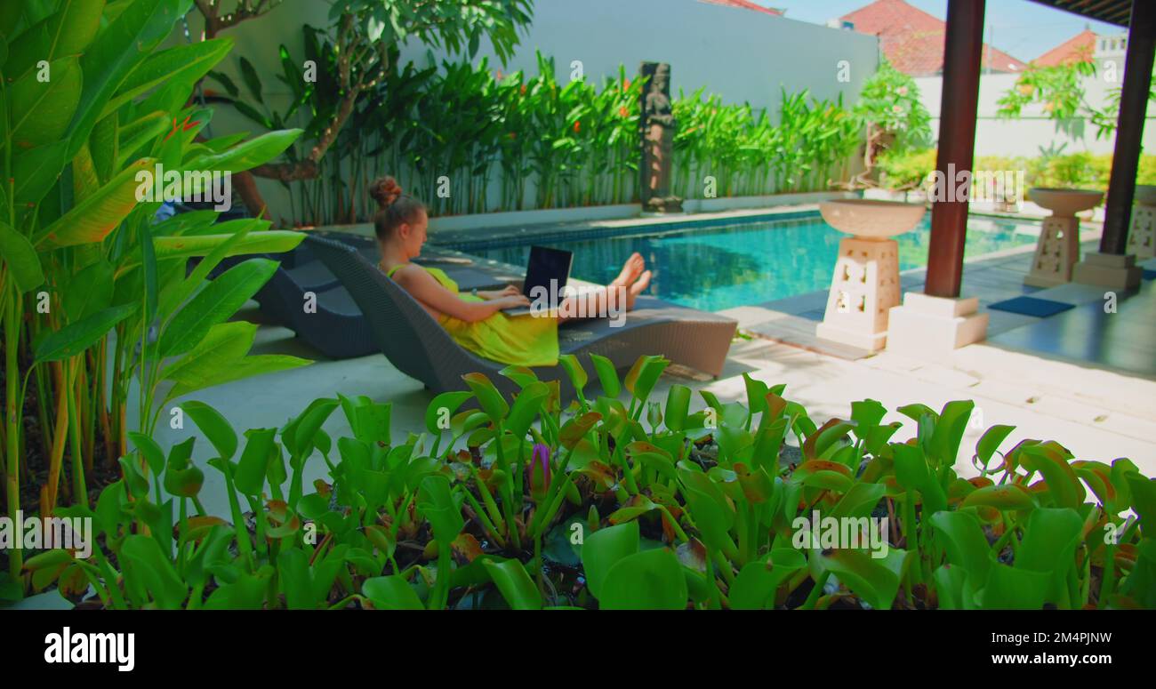 Young woman finish working on laptop relaxing by the swimming pool
