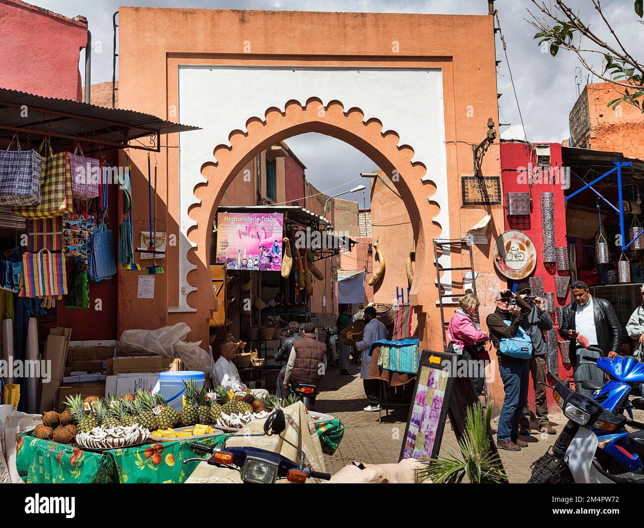Ornate gate in the bustling souk, colourful shops, stalls, tourists and passers-by, Medina, UNESCO World Heritage Site, Marrakech, Morocco Stock Photo