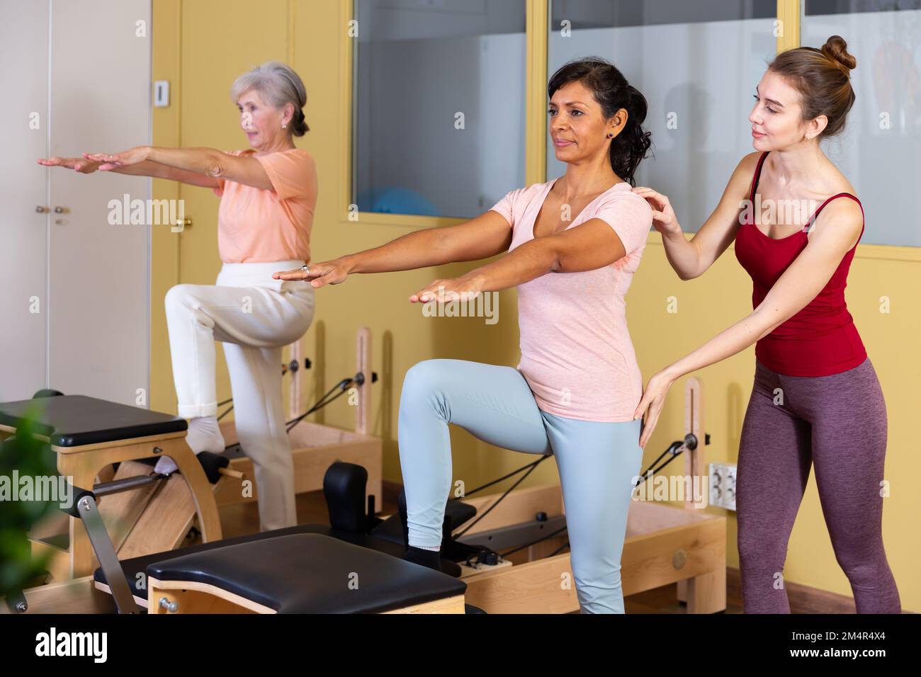 Young woman practicing pilates stretching exercises on combo chair