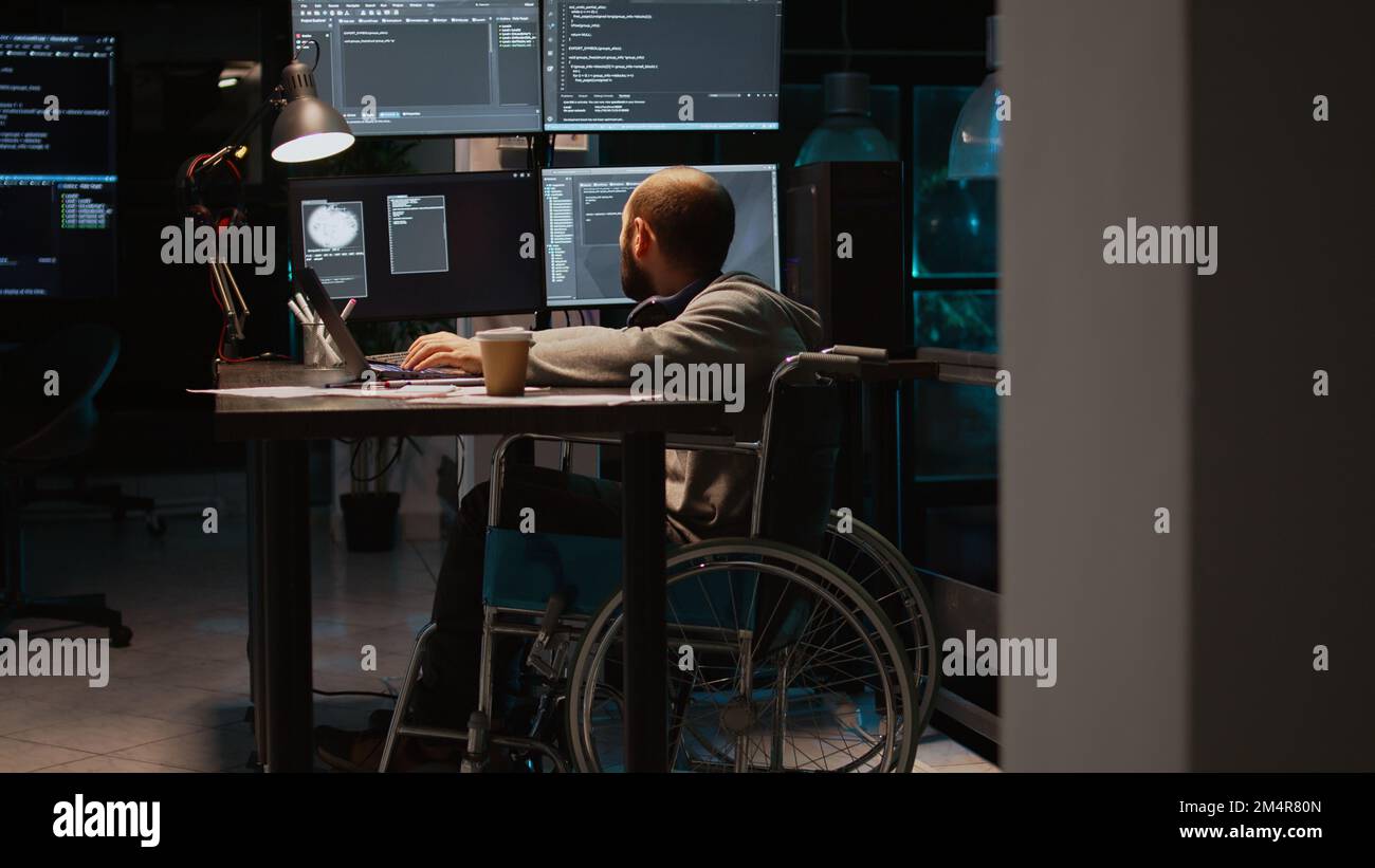App developer with physical disability working on IT software coding, using source code and big data. Programmer wheelchair user with impairment developing new user interface. Stock Photo
