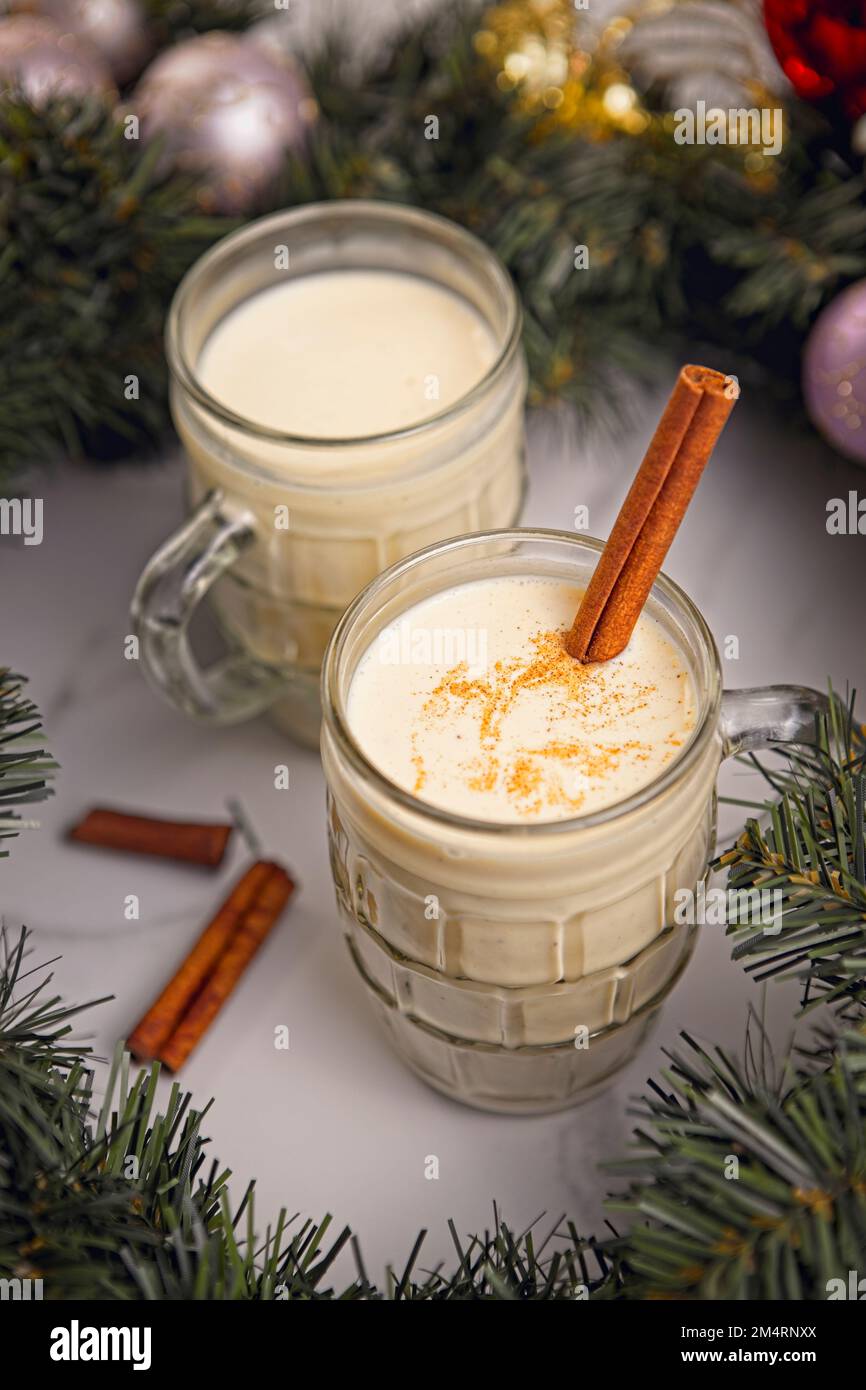 A close up concept photo of two glasses of eggnog with cinnamon sticks ...
