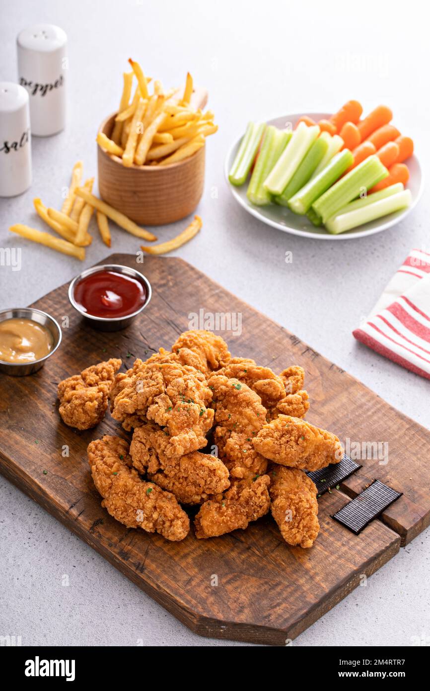 Fried chicken tenders or strips served with ketchup and fries Stock