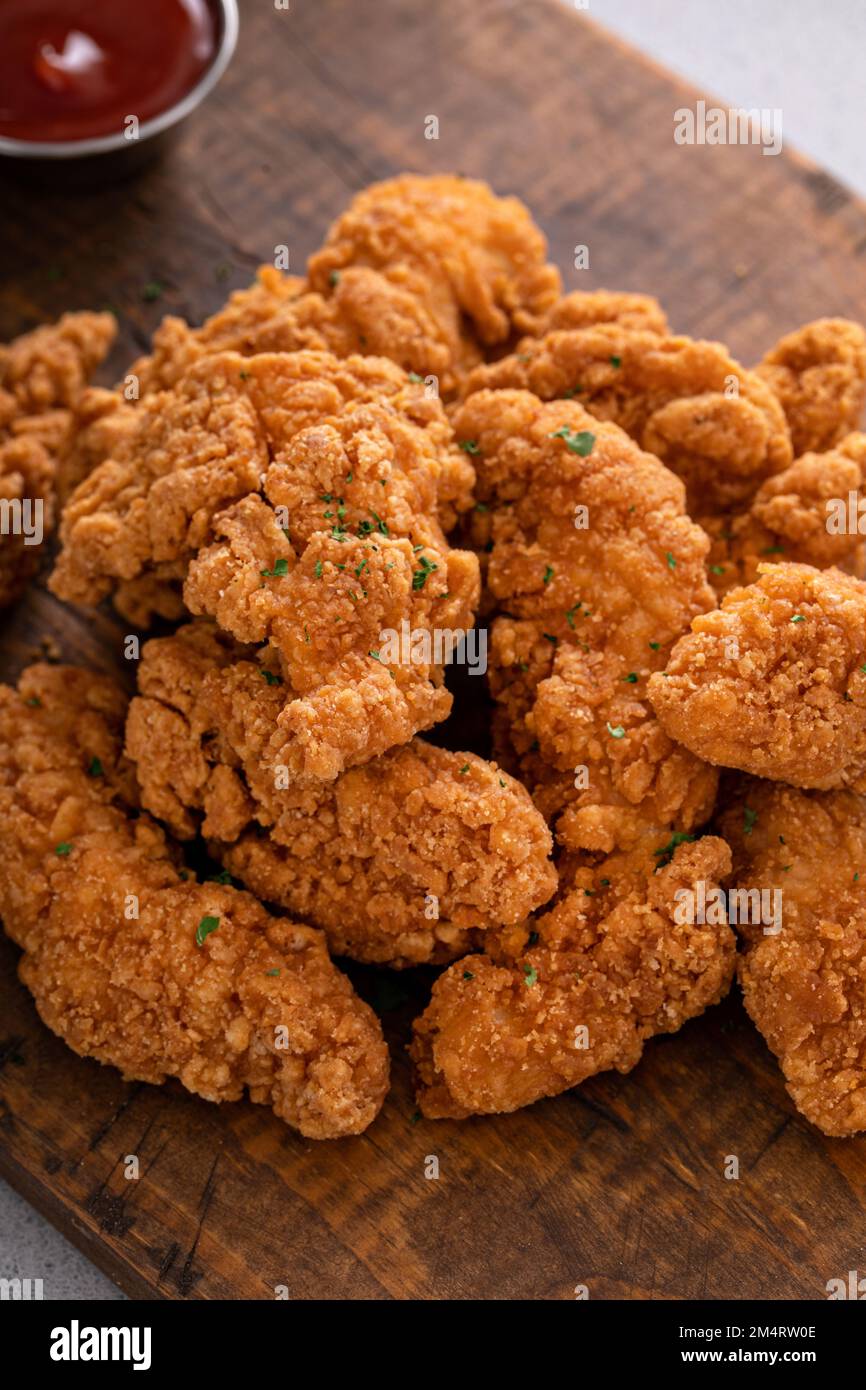 Fried chicken tenders or strips served with ketchup and fries Stock