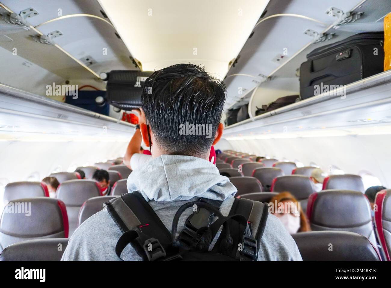 Passengers walk in the cabin of an airplane. an asian man walking down