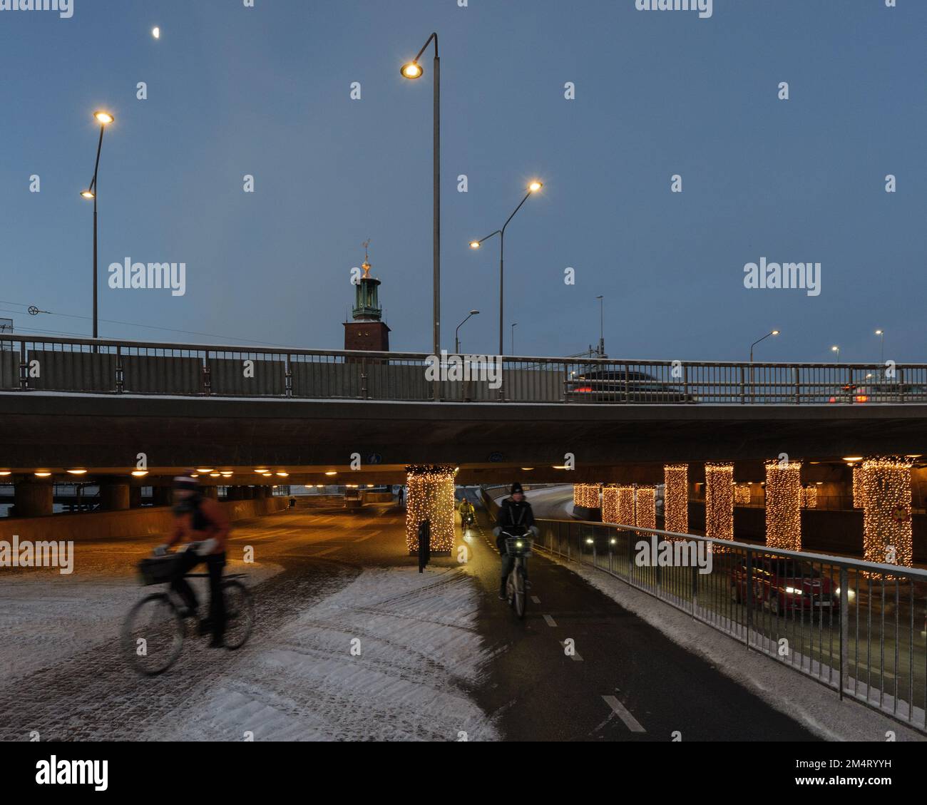 Commuters cycling in Stockholm city center decorated with Christmas lights at dawn in winter Stock Photo