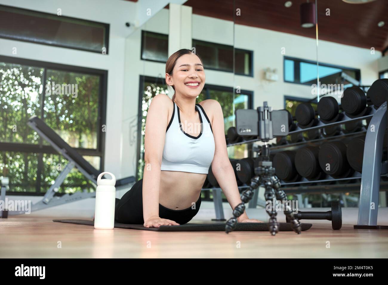Young woman watching fitness video or having video conference with fitness trainer at smartphone screen. Stock Photo