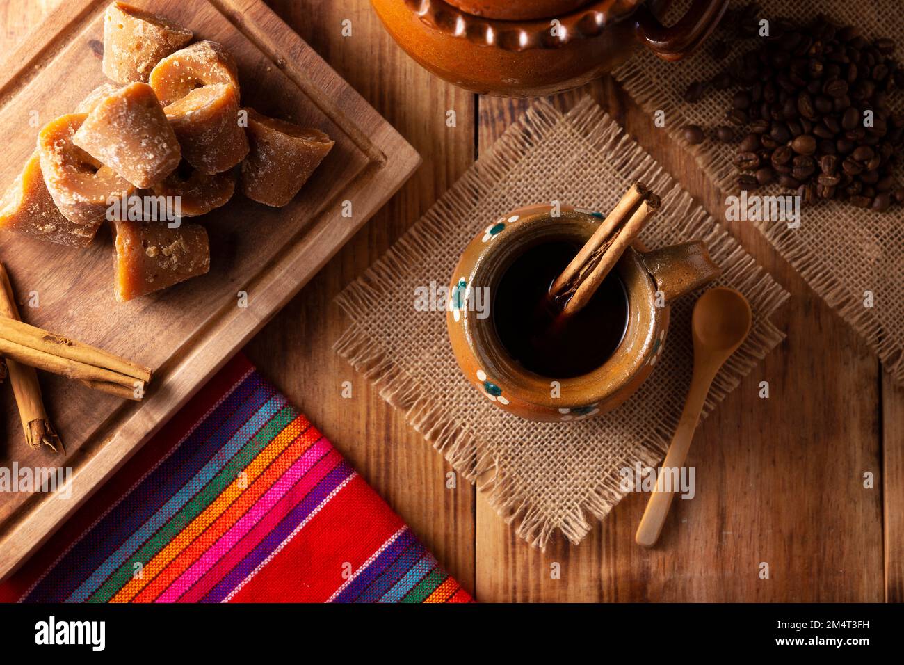 Authentic homemade mexican coffee (cafe de olla) served in traditional handmade clay mug (Jarrito de barro) on rustic wooden table. Stock Photo