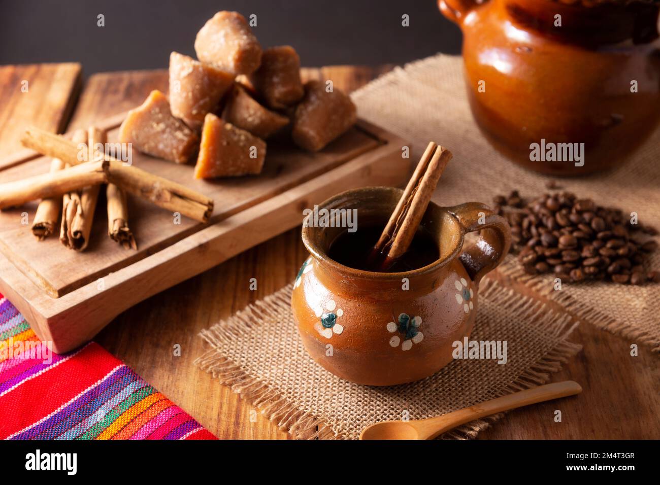 Authentic homemade mexican coffee (cafe de olla) served in traditional handmade clay mug (Jarrito de barro) on rustic wooden table. Stock Photo