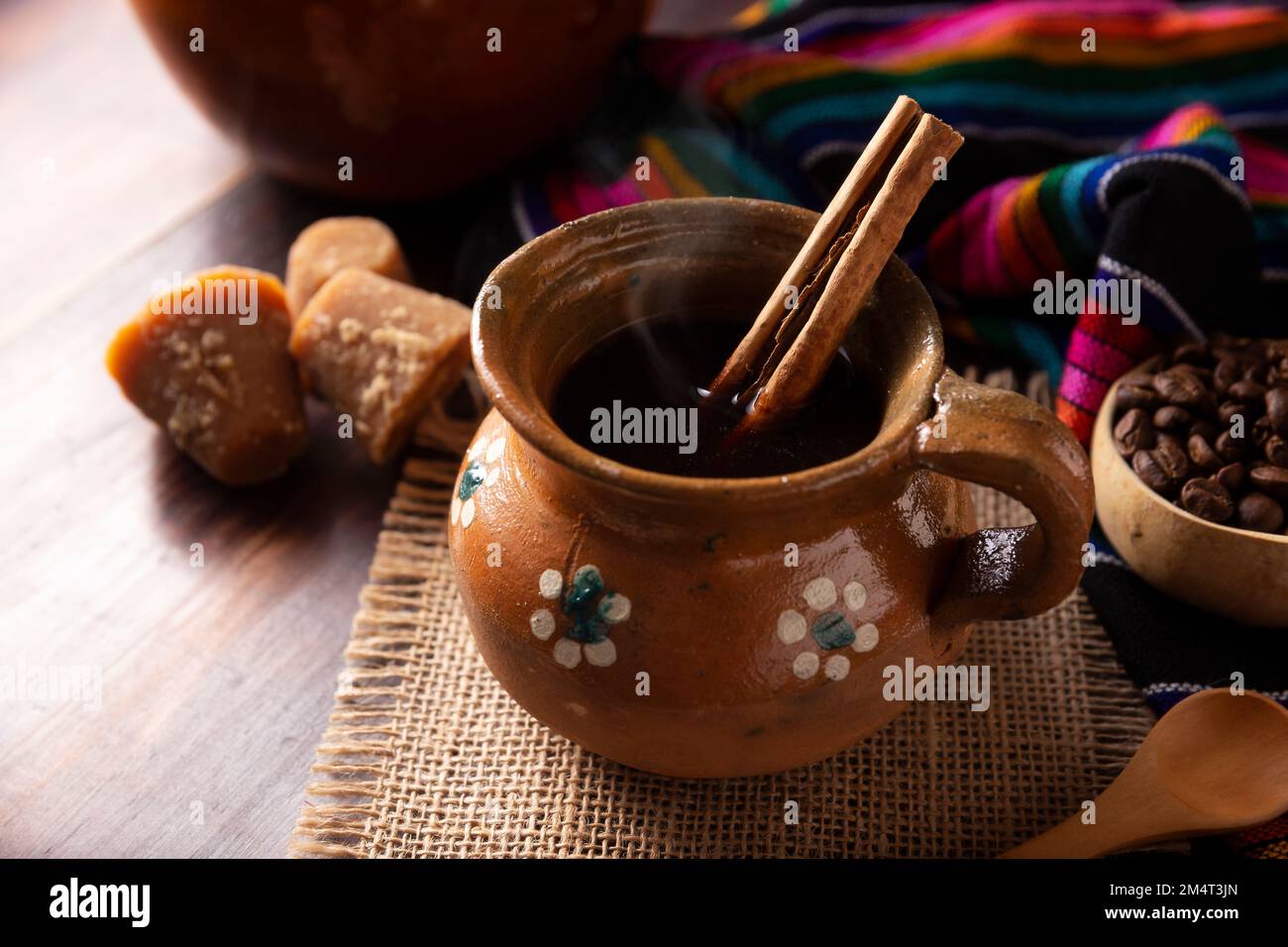 Authentic homemade mexican coffee (cafe de olla) served in traditional handmade clay mug (Jarrito de barro) on rustic wooden table. Stock Photo