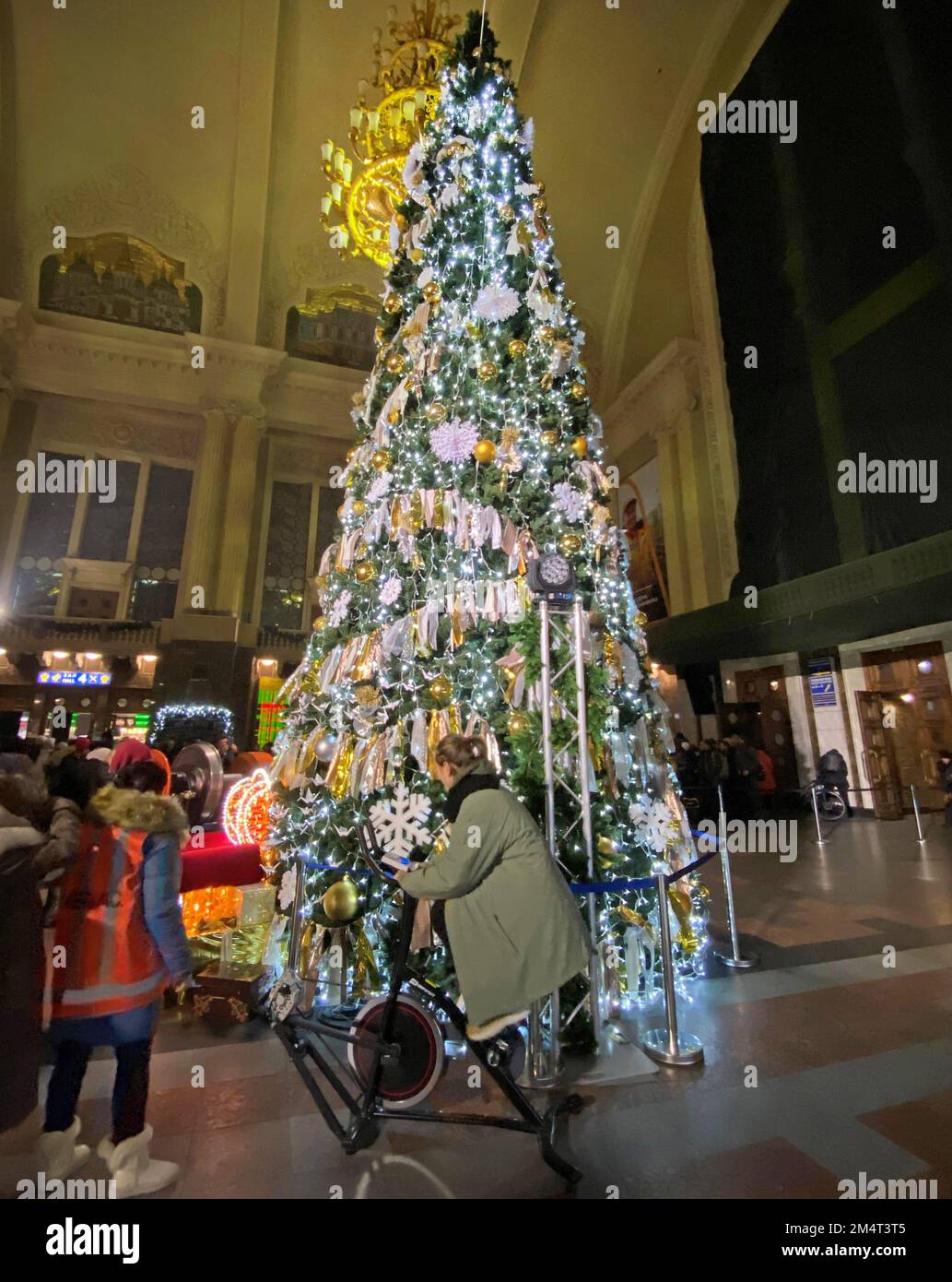 Kiew, Ukraine. 21st Dec, 2022. In the reception hall at the main station, a man on an energy bicycle pedals to light up the decorated tree. (To the KORR report: 'Dark Christmas in Kiev - Putin's war also shifts traditions') Credit: Ulf Mauder/dpa/Alamy Live News Stock Photo