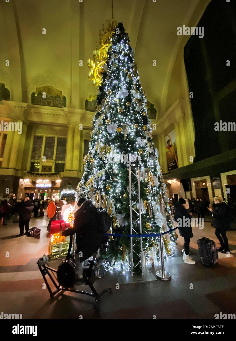 Kiew, Ukraine. 20th Dec, 2022. In the reception hall at the main station, a man on an energy bicycle pedals to light up the decorated tree. (To the KORR report: 'Dark Christmas in Kiev - Putin's war also shifts traditions') Credit: Ulf Mauder/dpa/Alamy Live News Stock Photo