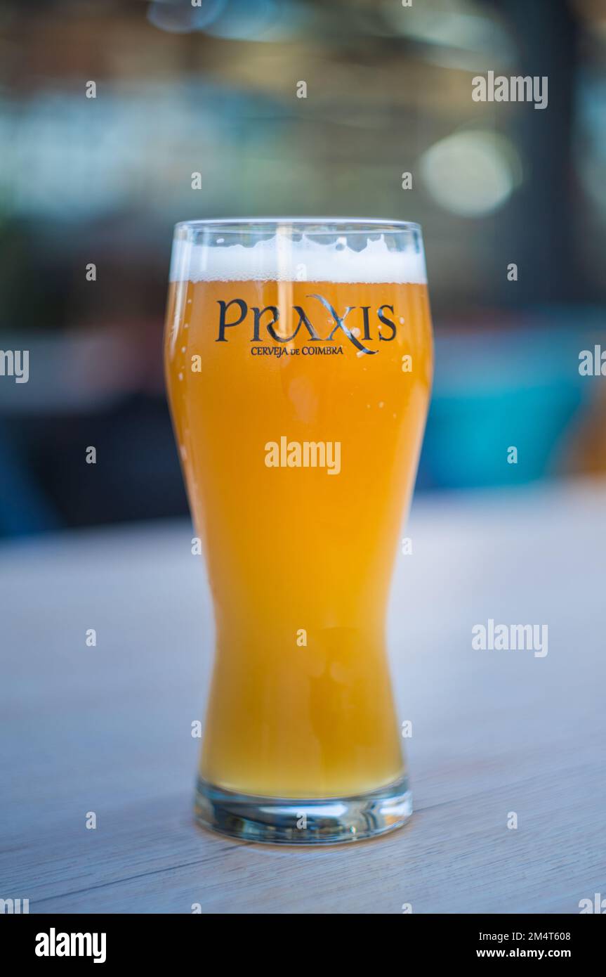 A vertical shot of a glass of beer with Praxis text in a bar in Coimbra, Portugal Stock Photo