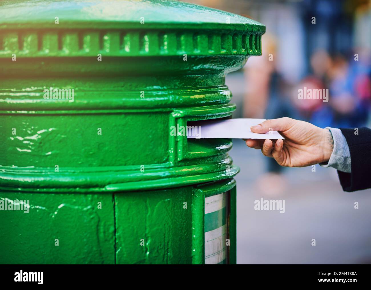 Theres still a place for snail mail in the world. a man posting mail into a postbox in the city. Stock Photo
