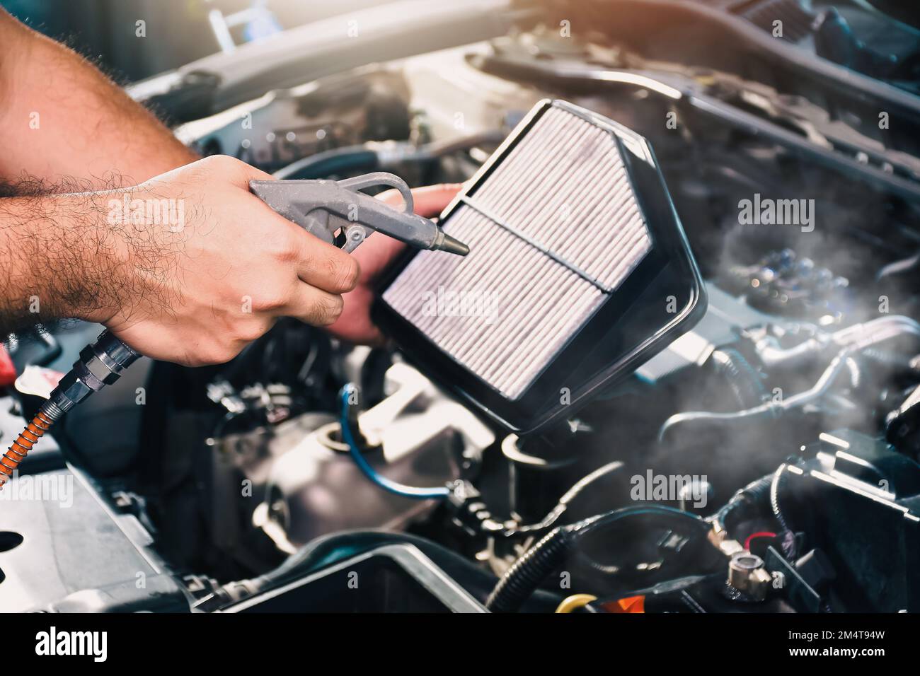 Auto mechanic is blowing dust and cleaning a car air filter with air blow gun, car maintenance service concept Stock Photo