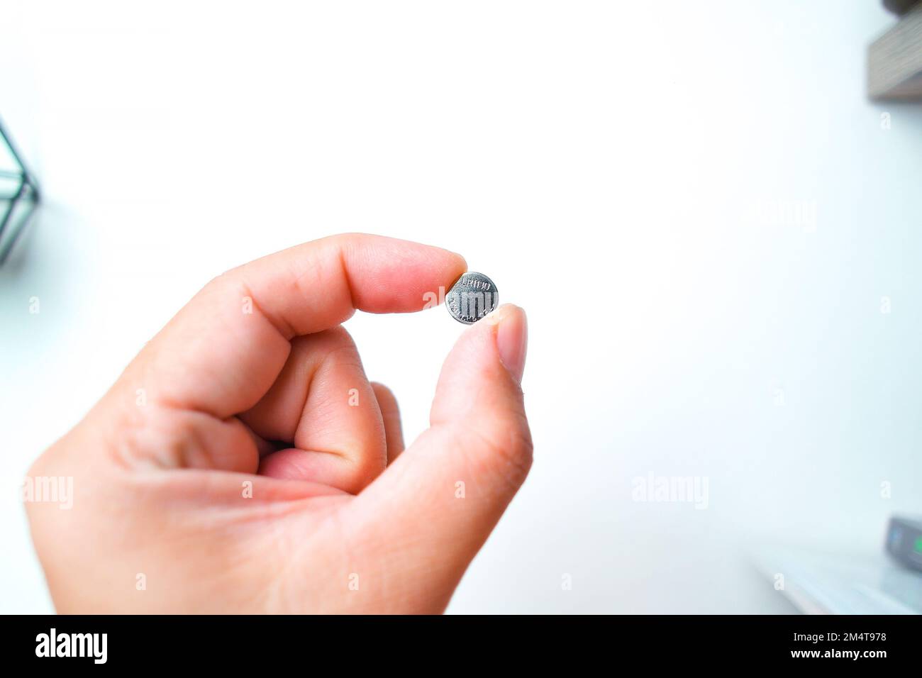 Coin cell or button cell battery LR1130 in hand, object isolated on