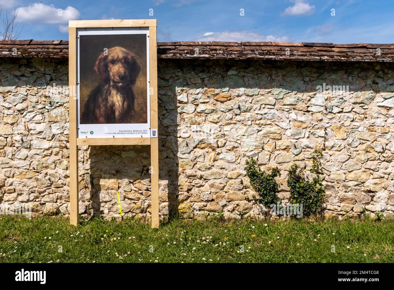 A reproduction of a 19th century painting showing a dog, installed outside against a limestone wall, taken in the town of Thomery, near Paris on an ea Stock Photo