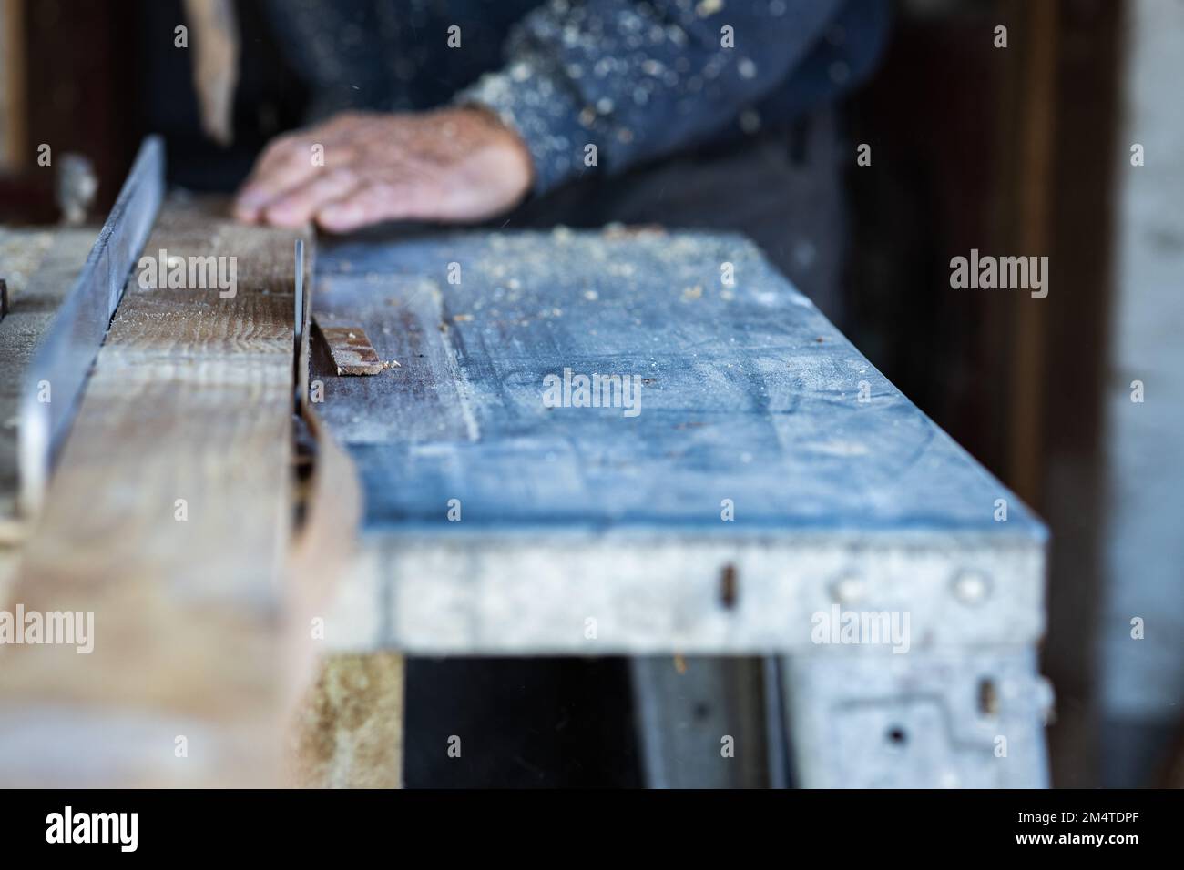 close-up photo of a circular saw cutting a wooden batten.in the blurred background is a worker's hand holding a wooden lath Stock Photo