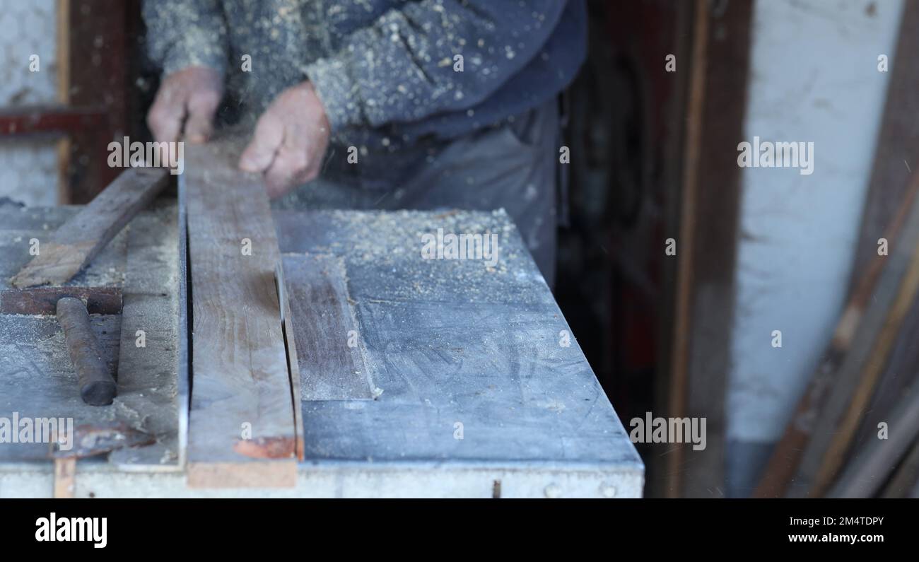 a carpenter cuts a batten on a table saw.in focus is a circular saw that cuts through the wood. a circular saw cuts wood. Stock Photo