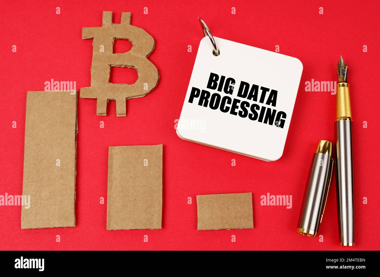 Business and bitcoin concept. On a red surface lie a bitcoin symbol, a graph, a pen and a notepad with the inscription - Big data processing Stock Photo