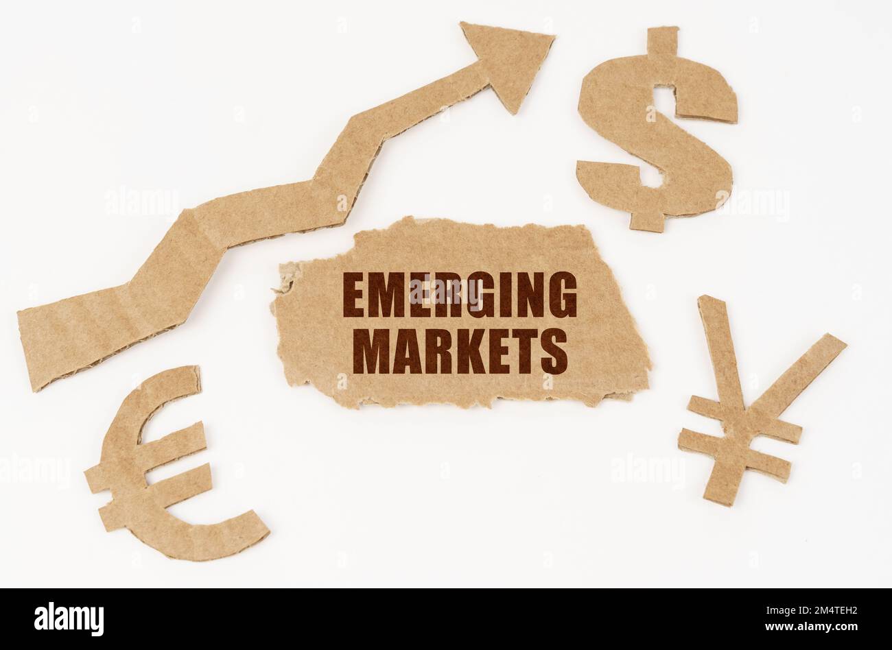 Economic concept. On a white background, symbols of the dollar, euro, yen, an arrow pointing up and a torn cardboard with the inscription - EMERGING M Stock Photo