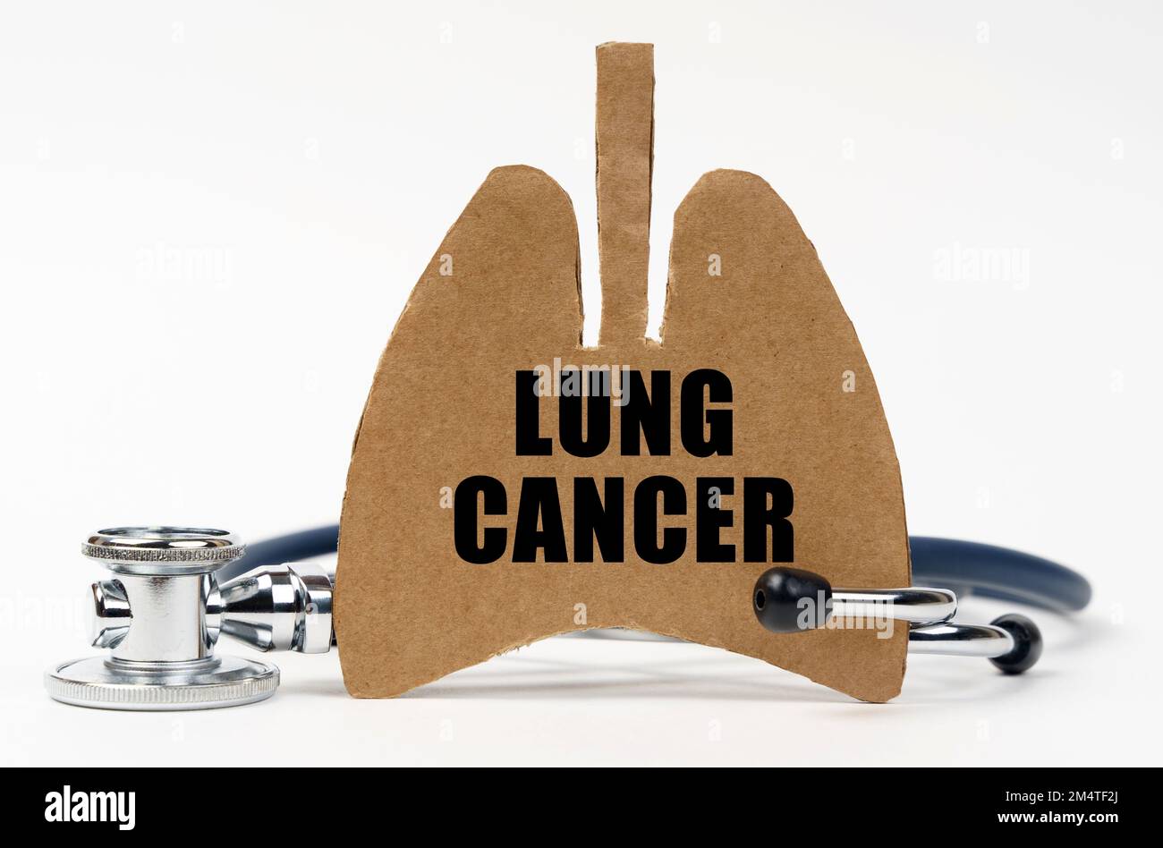 Medical concept. On a white surface are a stethoscope and a cardboard figure of a lung with the inscription - LUNG CANCER Stock Photo